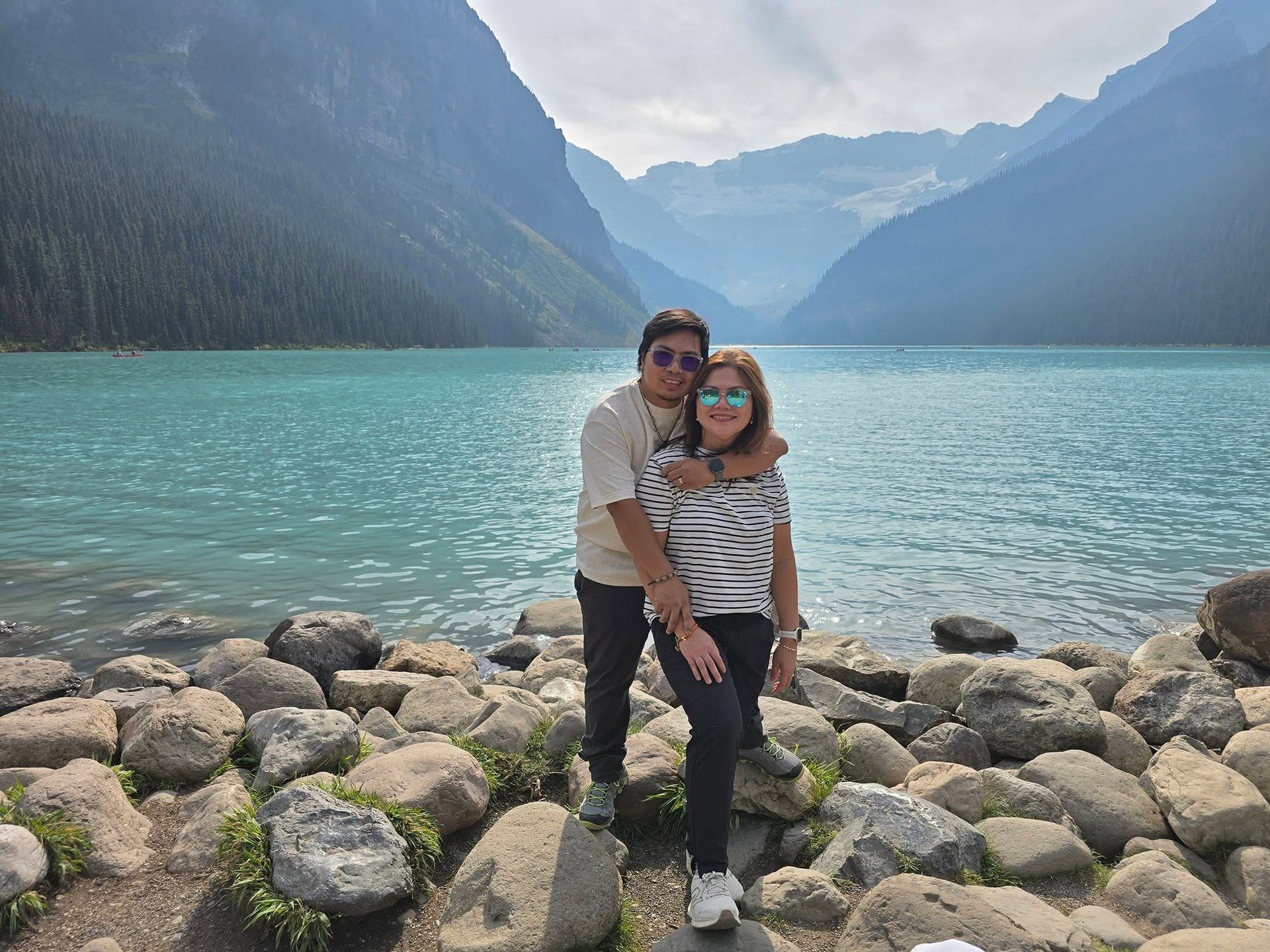 Rochelle and Nathaniel standing on the rocky shore of Lake Louise in Banff