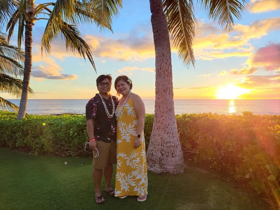 Rochelle and Nathaniel beneath palm trees at a golden Hawaiian sunset